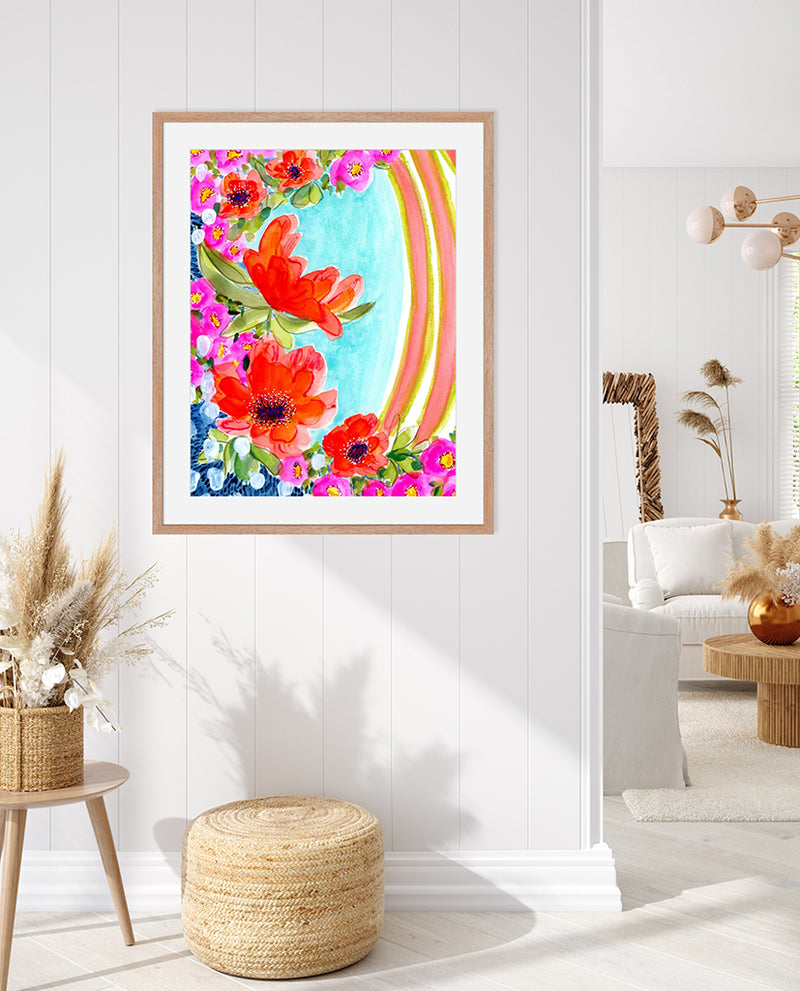 A vibrant watercolor mixed media fine art print featuring abstract floral elements in magenta, orange, and yellow with contrasting garden greens and sapphire blues, presented in a modern natural solid wood frame.