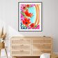 A vibrant watercolor mixed media fine art print featuring abstract floral elements in magenta, orange, and yellow with contrasting garden greens and sapphire blues, presented in a modern black metal frame.