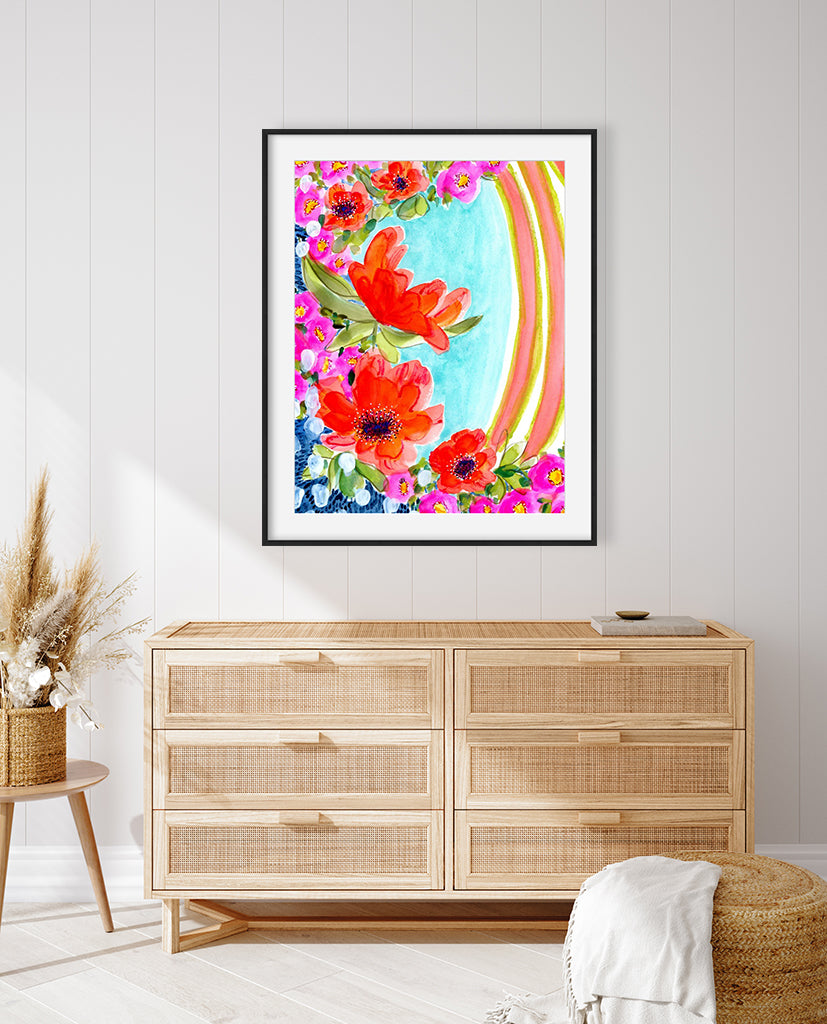 A vibrant watercolor mixed media fine art print featuring abstract floral elements in magenta, orange, and yellow with contrasting garden greens and sapphire blues, presented in a modern black metal frame.
