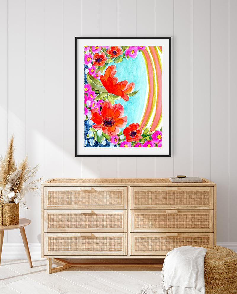 A vibrant watercolor mixed media fine art print featuring abstract floral elements in magenta, orange, and yellow with contrasting garden greens and sapphire blues, presented in a modern black metal frame.