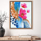 A framed abstract floral artwork featuring pink petals and deep browns and rich blues on a wall, with a wooden surface below.