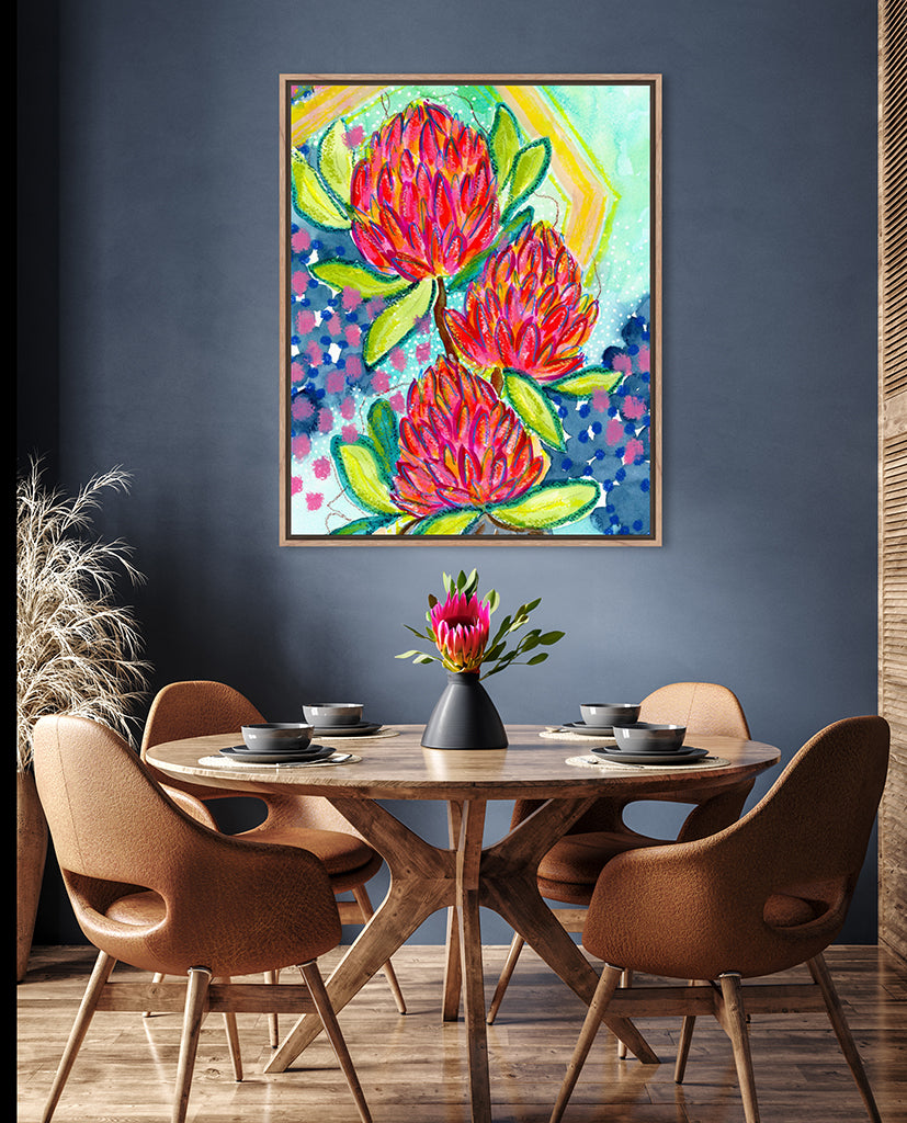 A vibrant abstract floral print with bold splashes of pink and red, and hints of yellow and blue, displayed on a wall above a dining table and chairs.