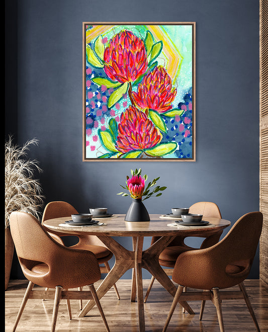 A vibrant abstract floral print with bold splashes of pink and red, and hints of yellow and blue, displayed on a wall above a dining table and chairs.